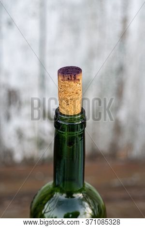 Side View Of Wine Bottleneck Closed With Cork Cap Stained By Dark Red Wine. Transparent Green Glass 