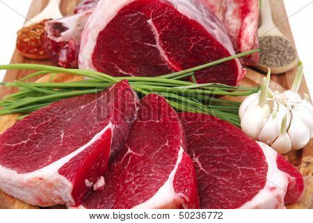 fresh meat : raw uncooked fat lamb pork rib and fillet with green stuff and red chili pepper on wooden plate isolated over white background