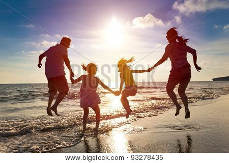 Happy Family Jumping Together On The Beach