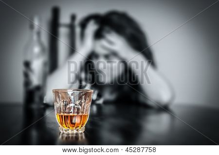 Alcohol addiction : Portrait of a lonely and desperate drunk hispanic woman (image focused on her drink)