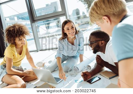 Share your thoughts. Joyful smart international students discussing their university project while sitting on the floor and studying together