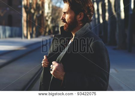 Portrait of mature man in coat standing outside at sunny evening elegant fashion model