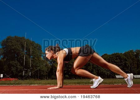 Athletic woman on track starting to run