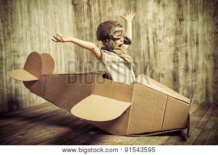 Cute dreamer boy playing with a cardboard airplane. Childhood. Fantasy, imagination. Retro style.