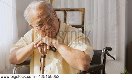 Pensive Disabled Elderly Patient Sit On Wheelchair Alone, Sad And Depressed Lonely Asian Senior Old 