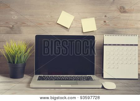 Wooden working table with laptop and calendar, in vintage tone.