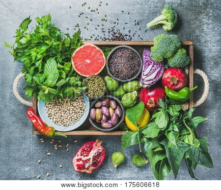 Vegetables, fruit, seeds, cereals, beans, spices, superfoods, herbs, condiment in wooden box for vegan, gluten free, allergy-friendly, clean eating or raw diet. Grey concrete background and top view