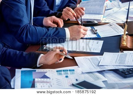 Business people office life of team people working with papers sitting table . Schemas and diagrams close up. Body part people in suits work in office and preparing for an economic project.