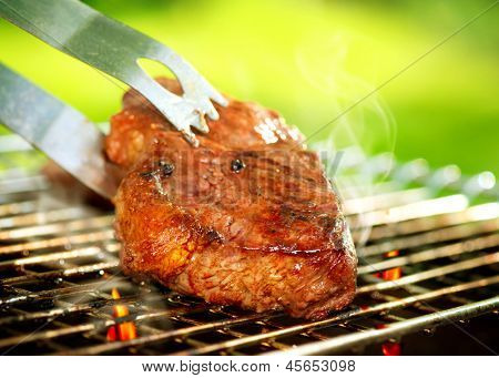 Flames Grilling a Steak on the BBQ. Grilled Meat Preparing. Grill Beef Steak Barbeque.  Barbecue outdoor. Barbecued Fillet