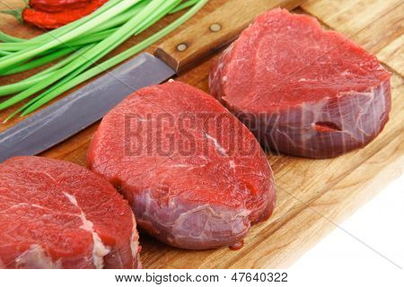 raw fillet chops : fresh beef meat with thyme and red hot dry pepper on wooden plate . isolated over white background