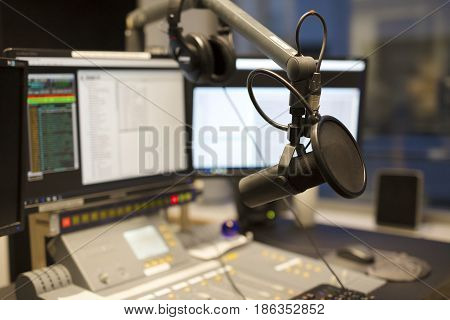 Microphone in front of the sound mixer and computers in broadcasting radio studio. New radio station studio.