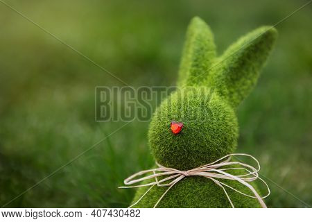 Close Up Easter Bunny Rabbit Statuette And Basket With Easter Eggs On The Green Grass Lawn Backgroun