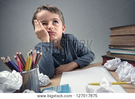 Thinking child bored, frustrated and fed up doing his homework