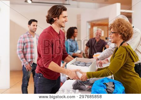 People Donating Food To Charity Food Bank Collection In Community Center