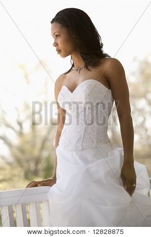 Portrait of African-American bride leaning against railing.