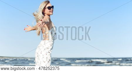 Happy Blonde Beautiful Woman On The Ocean Beach Standing In A White Summer Dress And Sun Glasses, Op