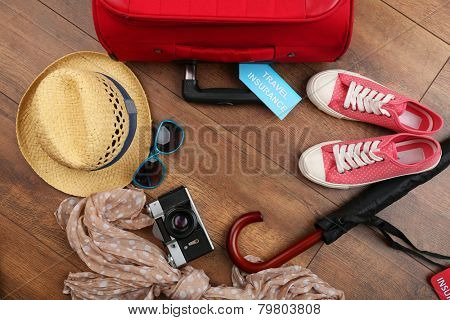 Suitcase and tourist stuff with inscription travel insurance on wooden background