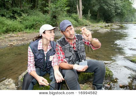 Man and woman fly fishing in river