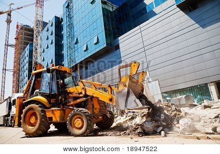 excavator is digging rubble in front of a modern building in construction