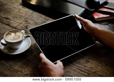 hands of a man holding blank tablet device over a wooden workspace table