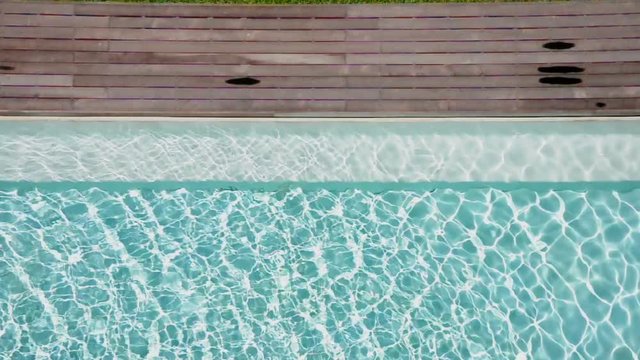 Shiny blue water in a swimming pool and wooden pathway. (HD footage with sound)