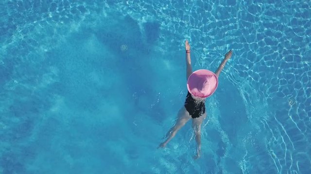 Young woman swimming in a swimming pool. Aerial footage