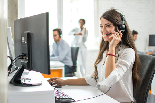 Friendly female customer service helpline operator working on computer in ofice 