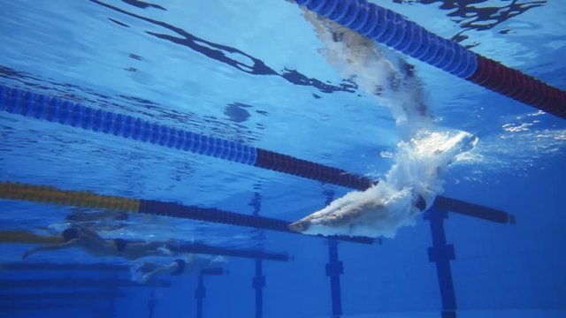 Muscular man under water in a swimming pool in super slow motion