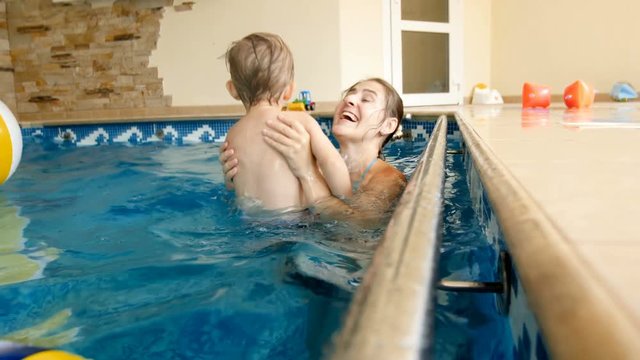 4k slow motion footage of happy smiling mother holding her child and throwing up in air at swimming pool