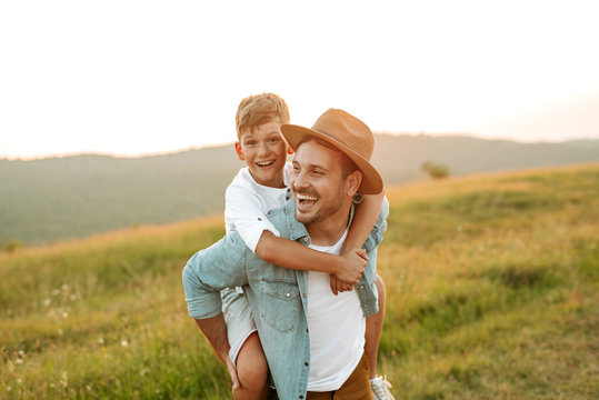 A mature father standing and holding a toddler son, having fun.