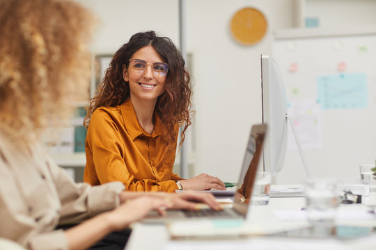 Two beautiful female colleagues interacting while working in office