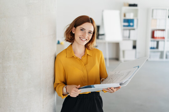 Attractive young office worker holding large file