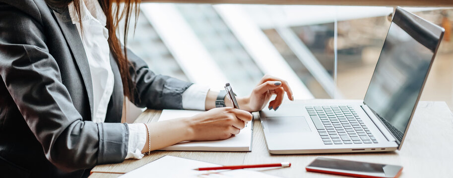 Girl works on a laptop in the workplace. Successful business woman creates a startup and makes decisions.