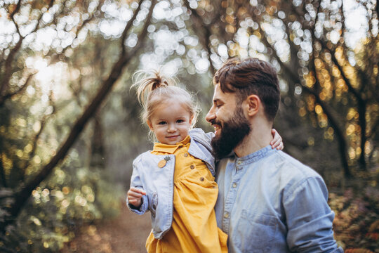 young, stylish bearded father walking with his little daughter in nature at sunset. Family photos of father and one child. selective focus, noise effect