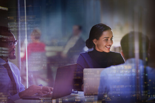 Smiling businesswoman at laptop in meeting in highrise office