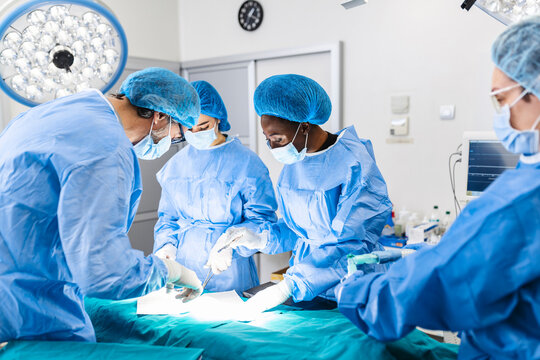 Surgical team performing surgery in modern operation theater,Team of doctors concentrating on a patient during a surgery,Team of doctors working together during a surgery in operating room,