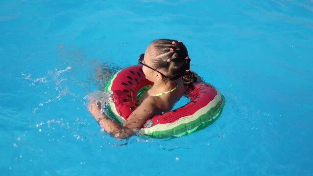 happy little girl enjoys summer swimming in swimming pool with swimming circle. High quality 4k footage