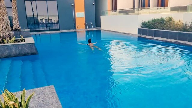 Footage of the young woman swimming in the pool. Activities