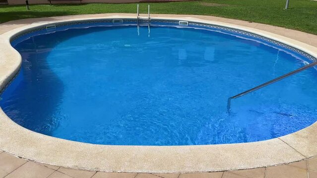 Empty swimming pool with transparent blue water in sunny day,Side view. Happy summer holidays concept. High quality 4k footage