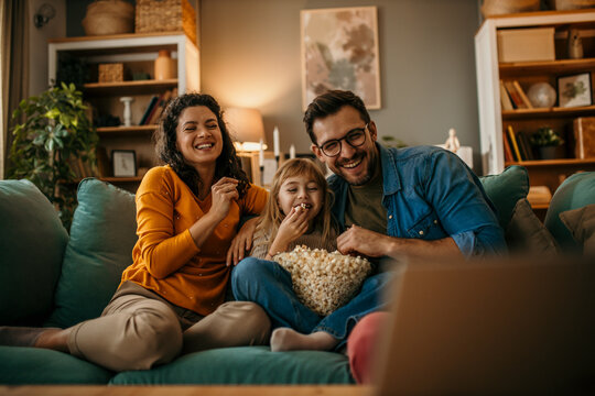 The joy of togetherness as a mom, dad, and daughter share a movie and popcorn in their living room