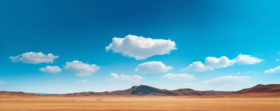 Vast desert landscape with mountains under a bright blue sky and scattered clouds. Nature and wilderness concept