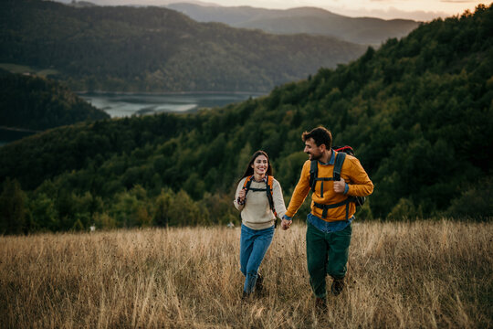 Couple holding hands and trekking together with an amazing view in the background