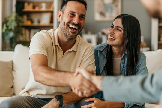 The young happy couple and an agent in a new property, or a professional psychologist advising spouses helping them restore marriage, and handsaking