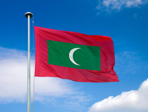 Maldives flag waving in the wind against a blue sky background