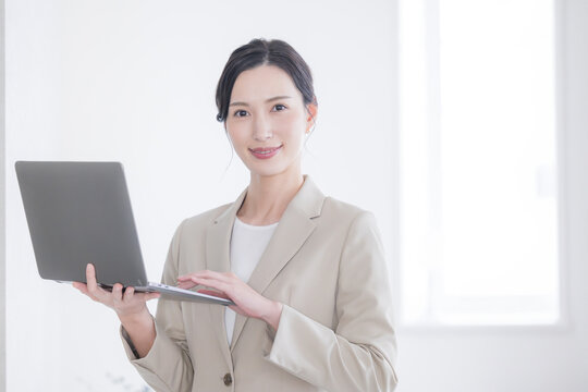 A beautiful woman in a suit holding a computer and looking at the camera A cool image of a consultant or secretary