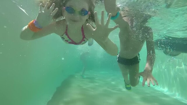 Happy girl and boy swimming under water. High quality 4k footage