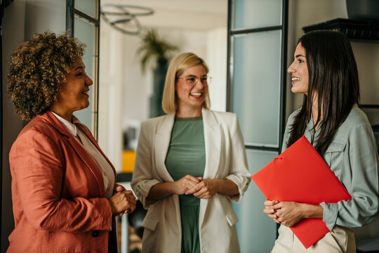 Smiling businesswoman and job candidate walking into an office and meeting her new team members.