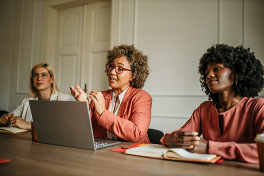 Female manager discussing a new project with her colleagues. The company owner on a meeting with her employees in her office.