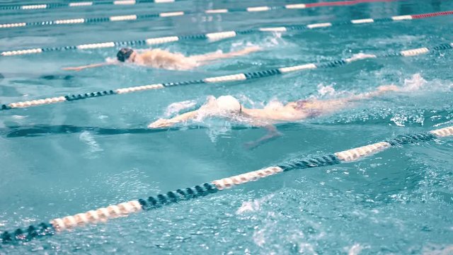 High angle three swimmers having competition in swimming pool tracking shot