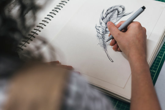 Cropped image of female artisan drawing on book in workshop